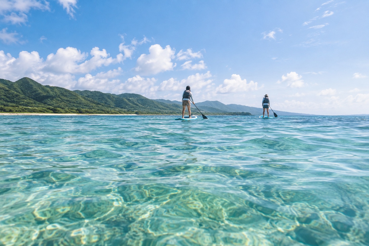 透明な海を穏やかに進む2人のSUPパドラーのデモ写真